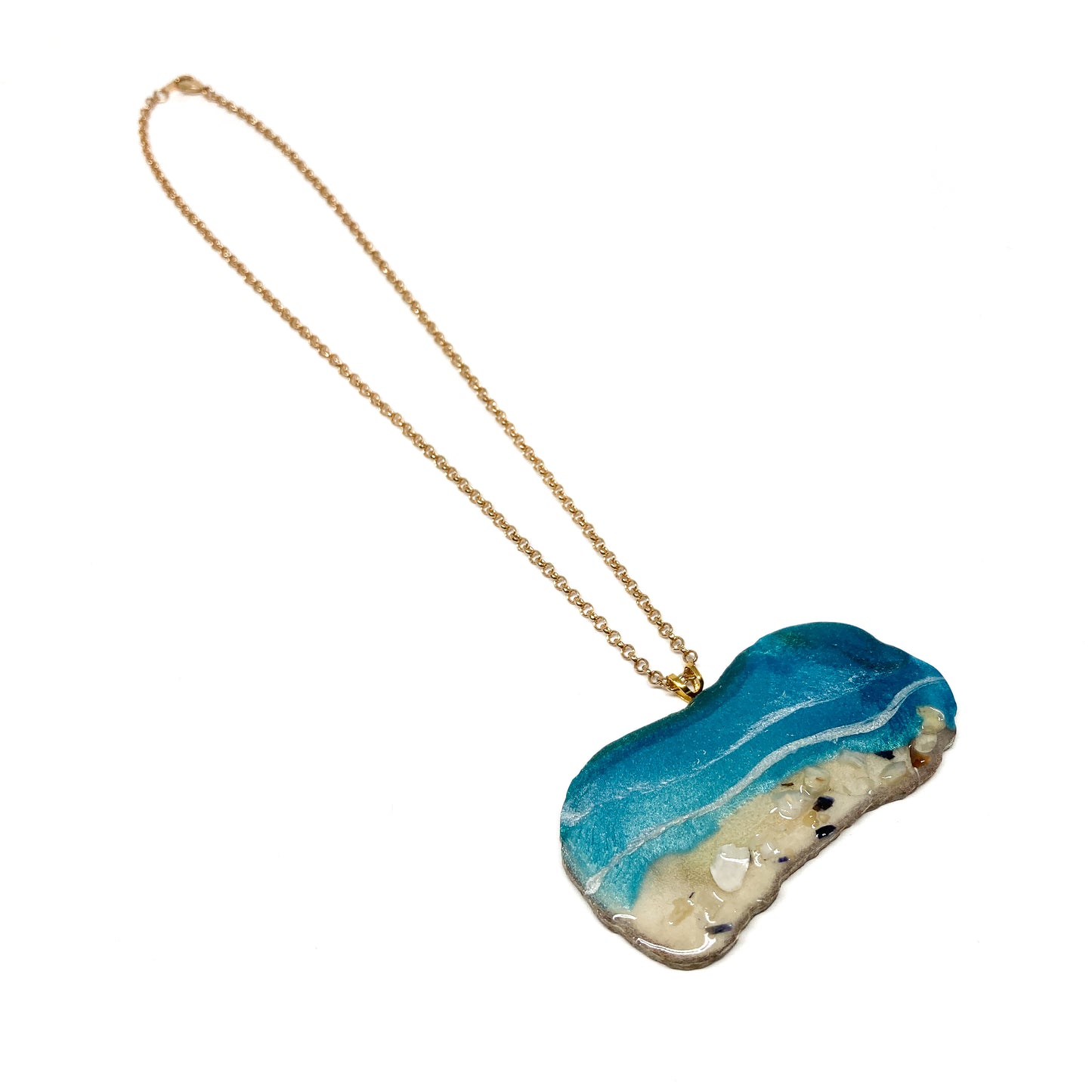 A necklace with an ocean-inspired pendant, featuring blue resin and sand-like textures.