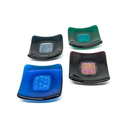 Four dichroic glass bowls in blue, green, dark, and black with iridescent centers.