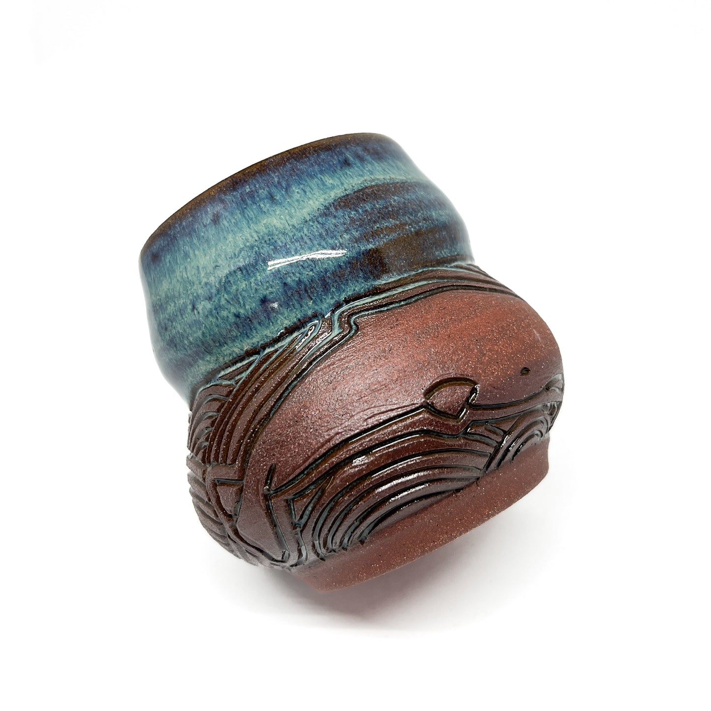 Small ceramic cup with a carved whale design on a textured brown base and a glossy blue-green rim.
