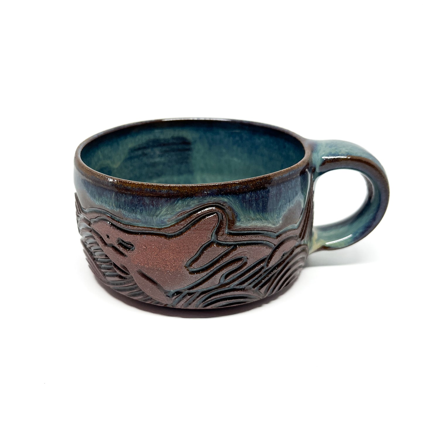 Handcrafted ceramic mug with an embossed orca whale design and a smooth, glazed finish.