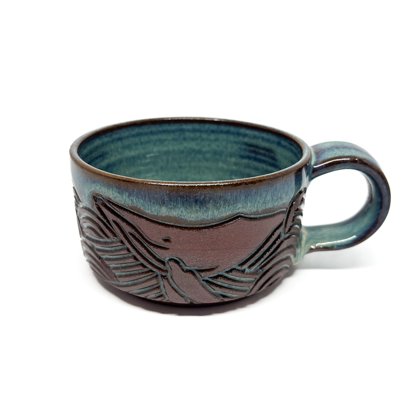 Ceramic mug with a raised whale tail design and a glossy, handcrafted finish around the exterior.