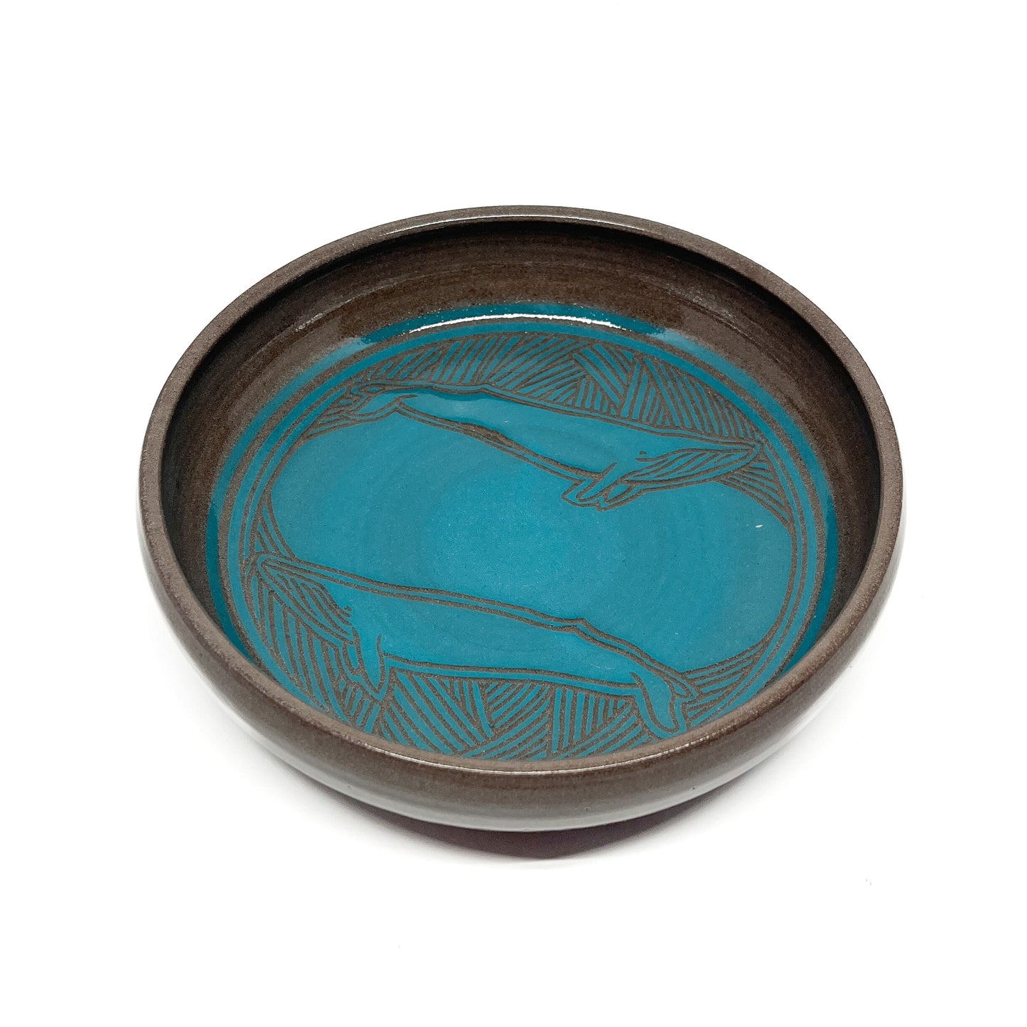 A teal and brown ceramic bowl with an etched, abstract design.