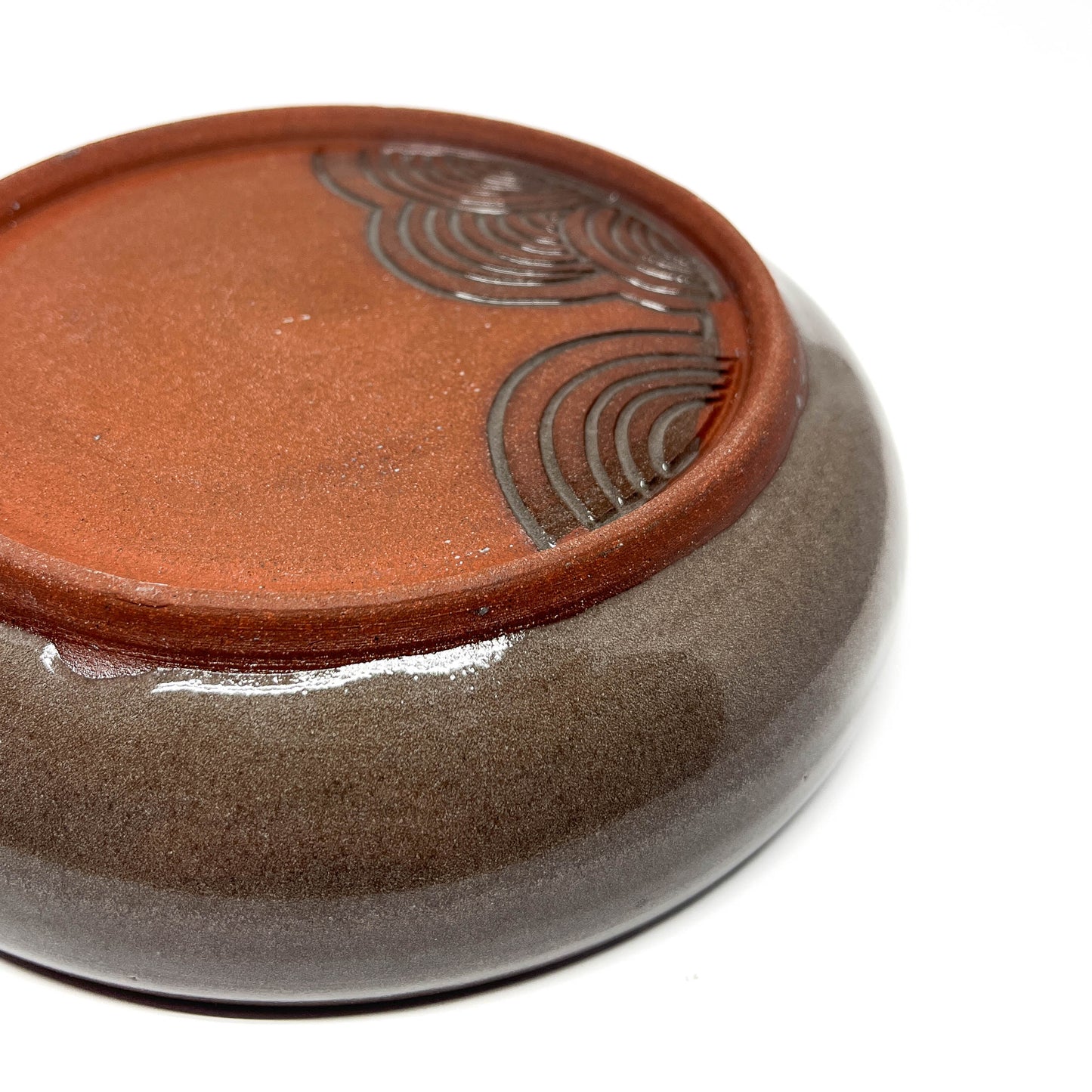 A grey and red ceramic covered box with a circular design on the lid.