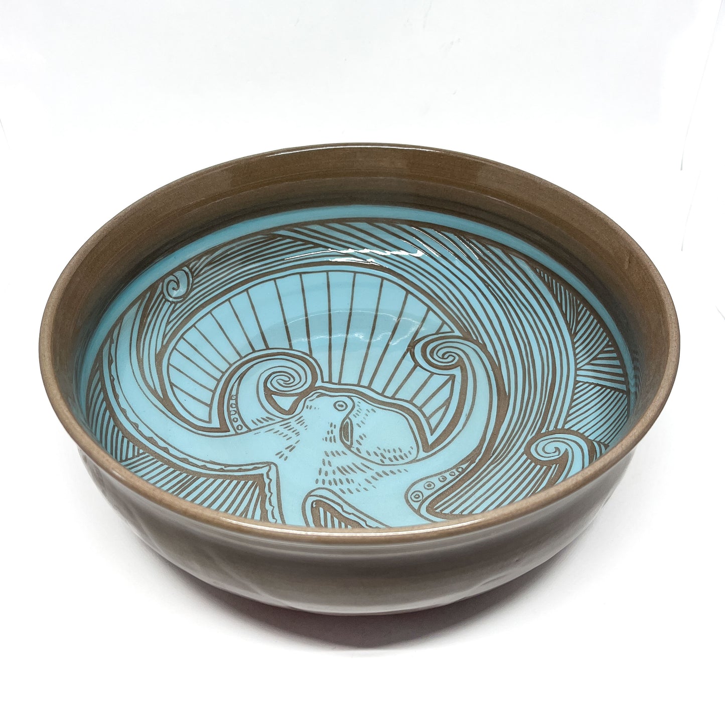 Ceramic bowl with a detailed octopus carving shown from an angled perspective to highlight depth.