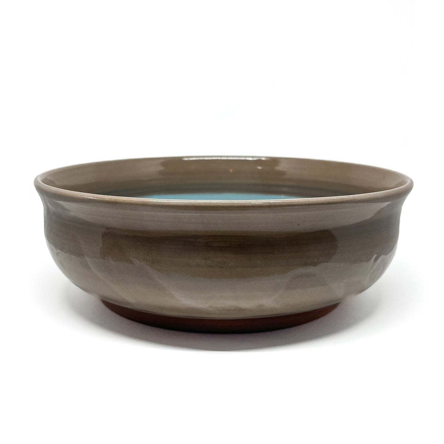 Bottom of a ceramic bowl with a carved whale and wave motif etched into the unglazed base.