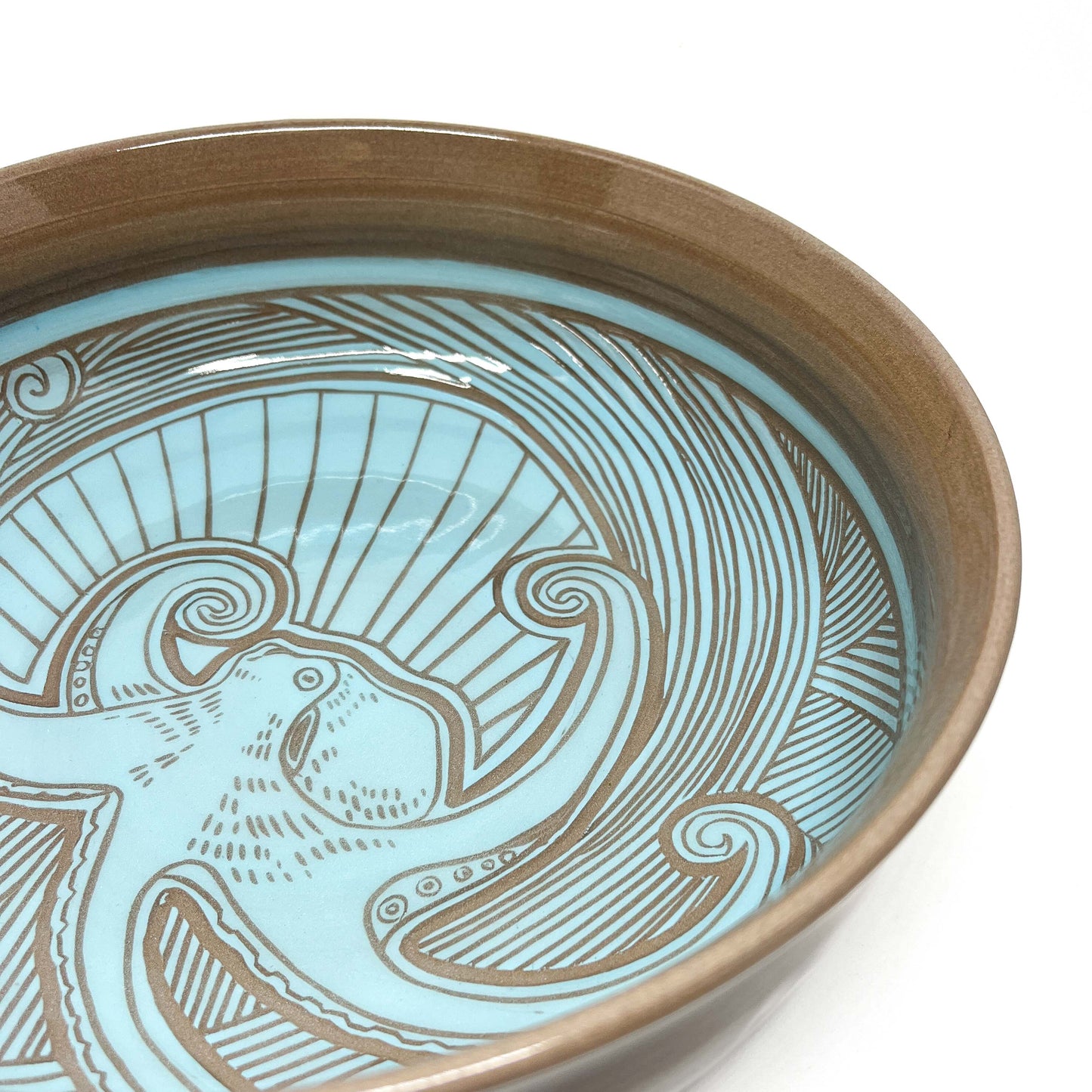 Angled close-up of a bowl interior with a carved humpback whale, spiraling waves, and radiating lines.
