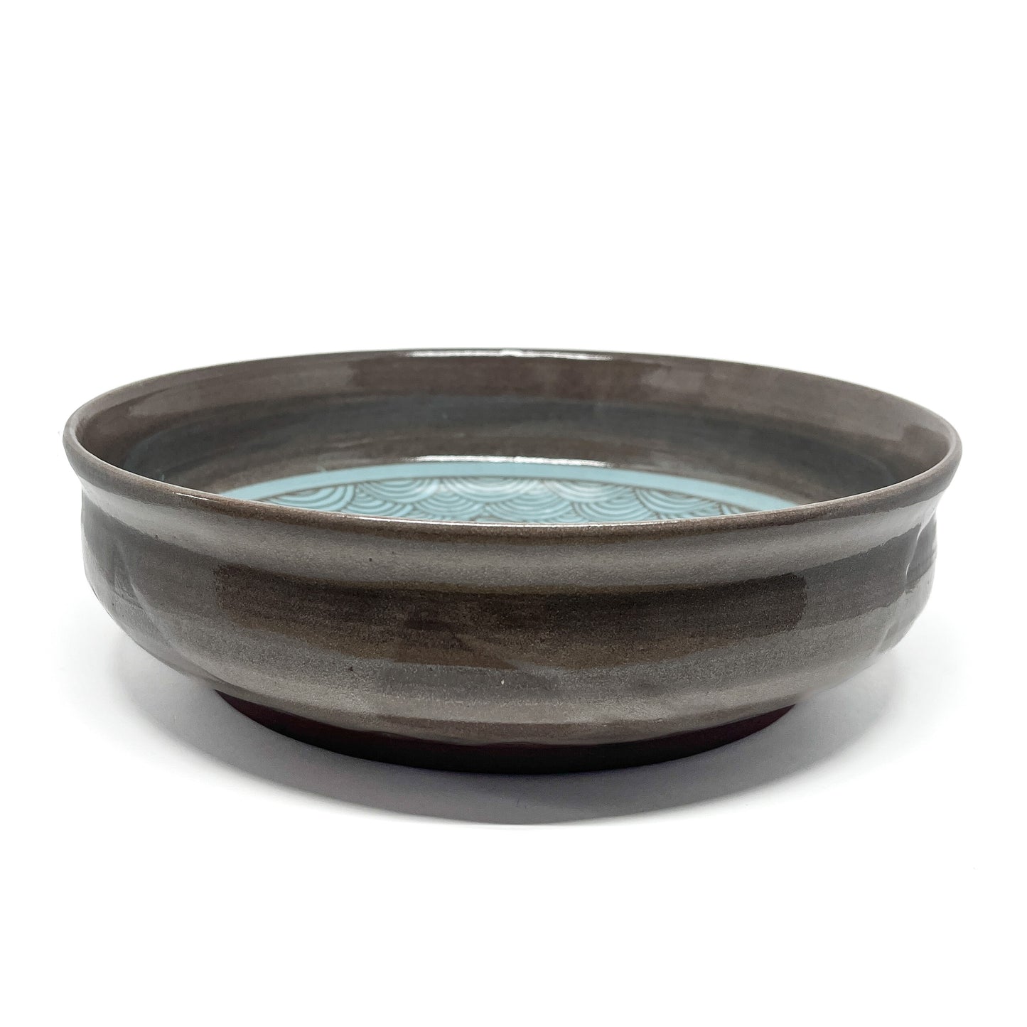 Underside of a ceramic bowl showing unglazed reddish-brown base with no visible design.