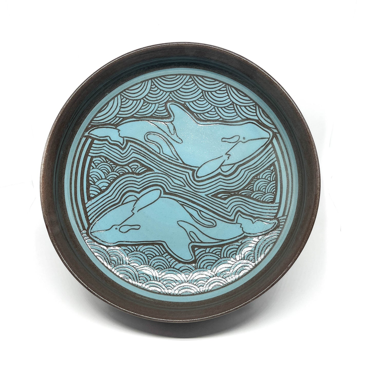 Side view of a bowl with a whale in the center, surrounded by arched and radiating wave patterns.
