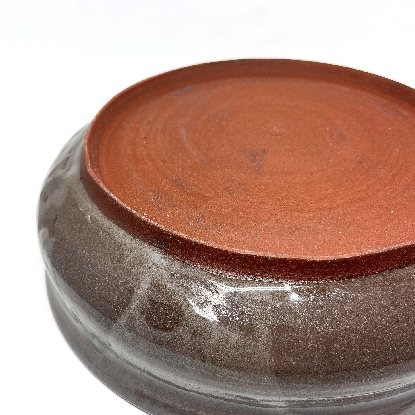 Underside of a ceramic bowl showing unglazed reddish-brown base with no visible design.