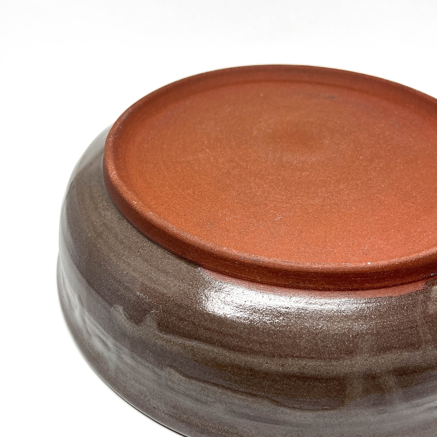 Bottom view of a ceramic bowl showing an unglazed foot and textured surface detail.