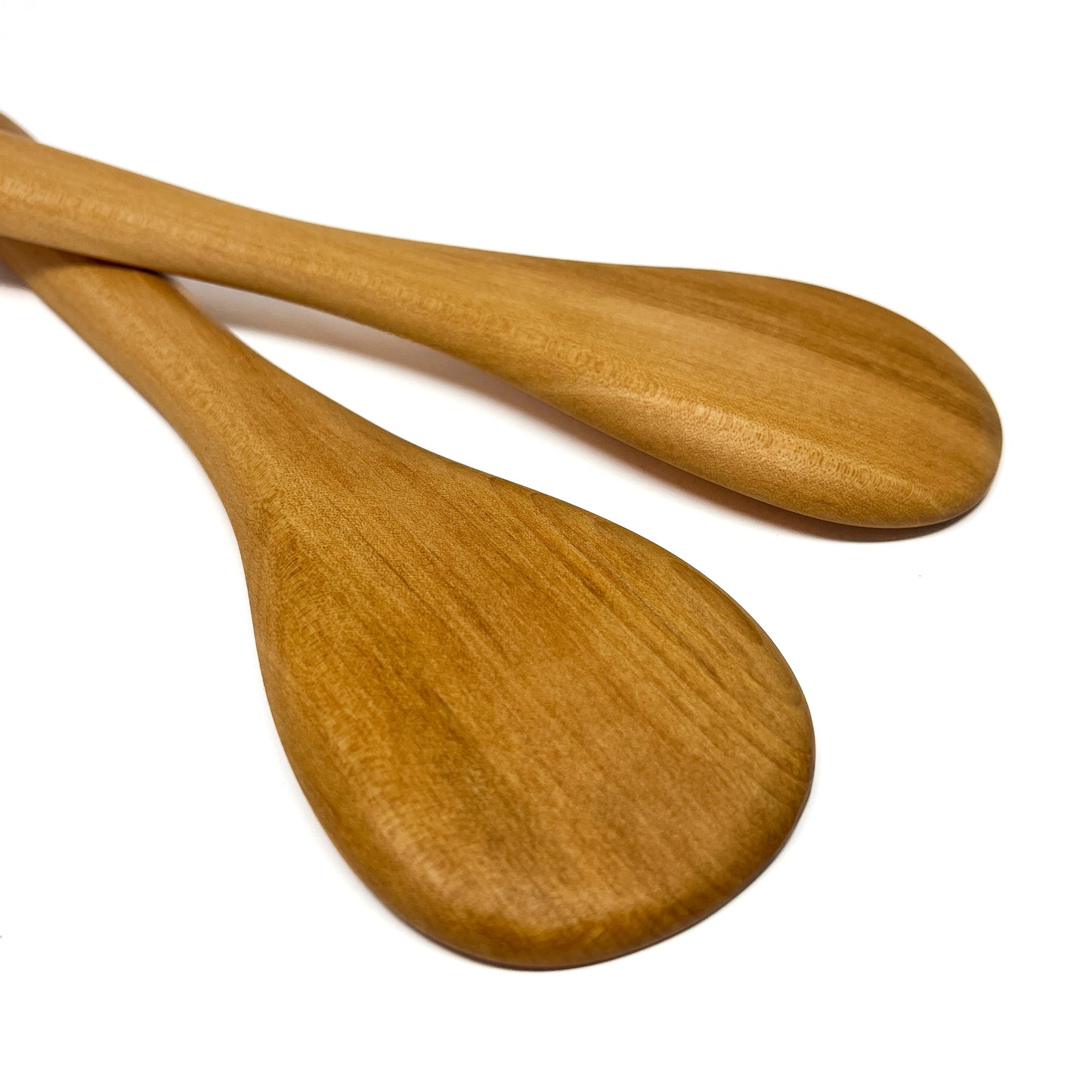 Two wooden spatulas crossed on a white surface.