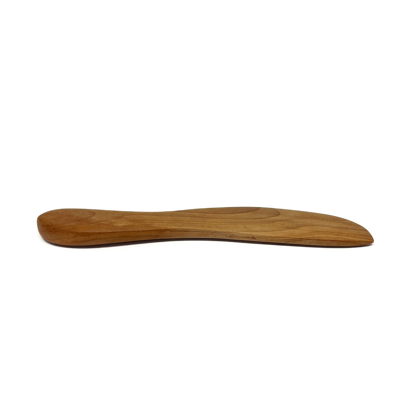 A wooden spread knife, angled on a white surface.