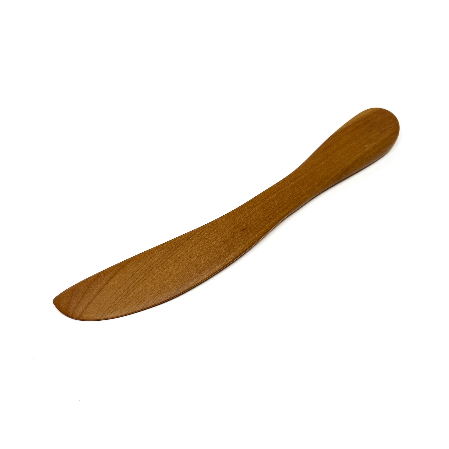 A wooden spread knife, angled on a white surface.