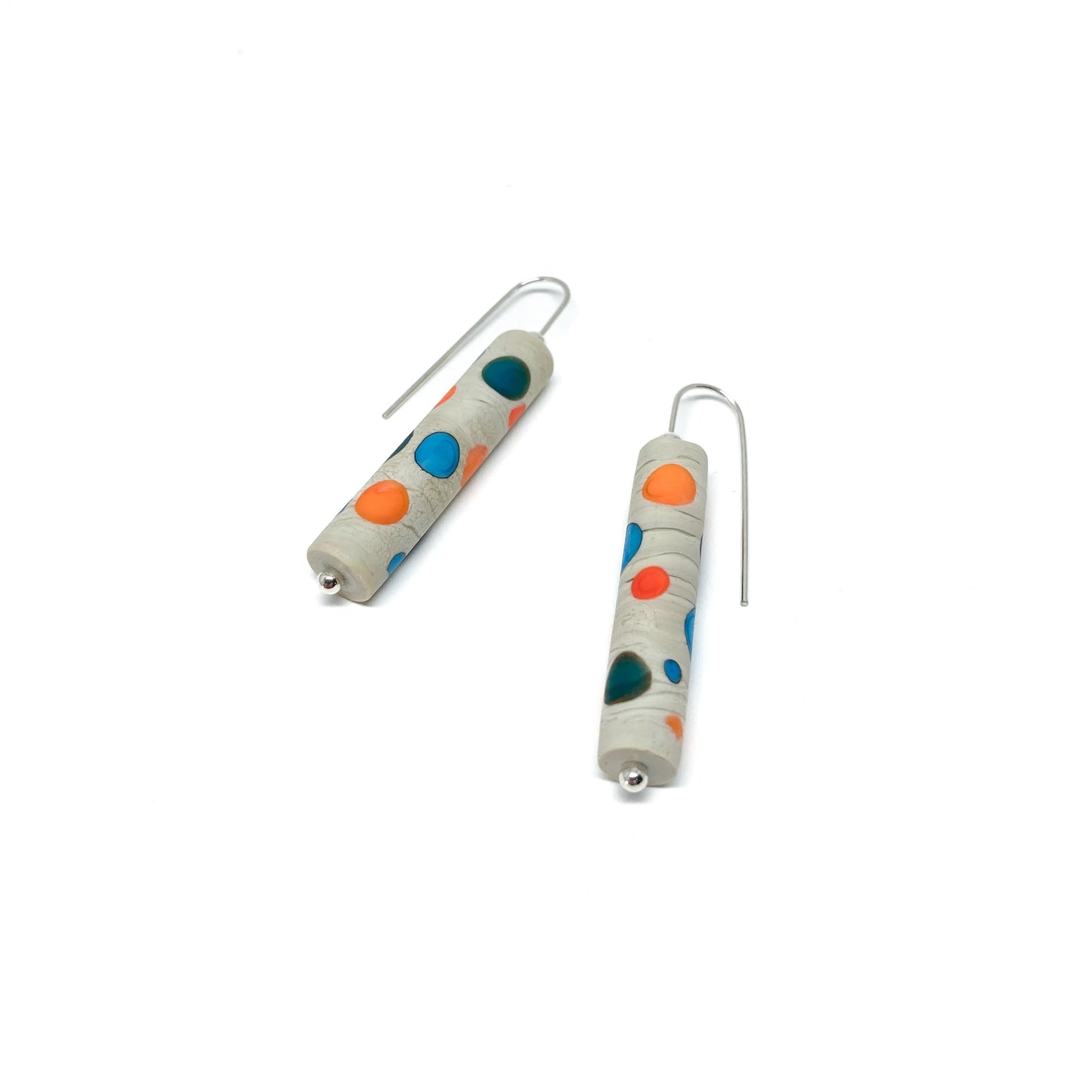 Two cylindrical earrings with teal, blue, and orange dots, silver hooks, and small silver beads.