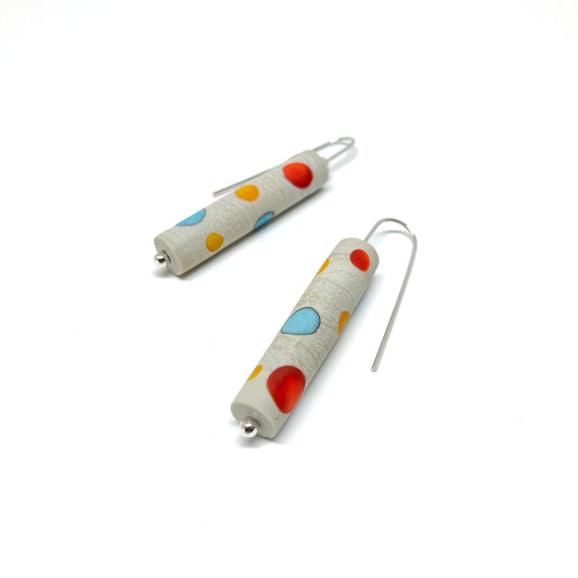 Two cylindrical earrings with colorful dots, silver hooks, and small silver beads.