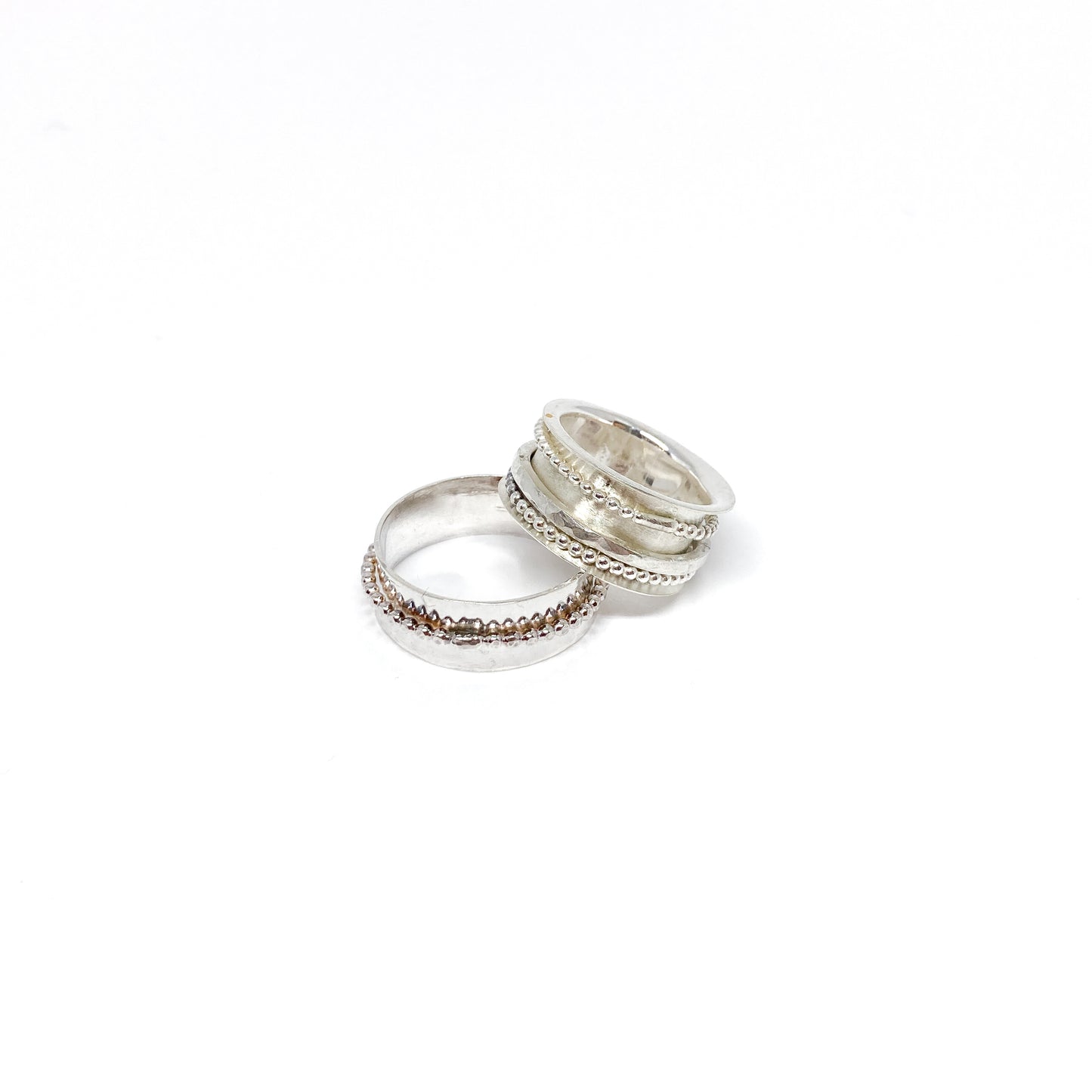 Two sterling silver spinner rings, one stacked, with beaded and textured spinning bands.
