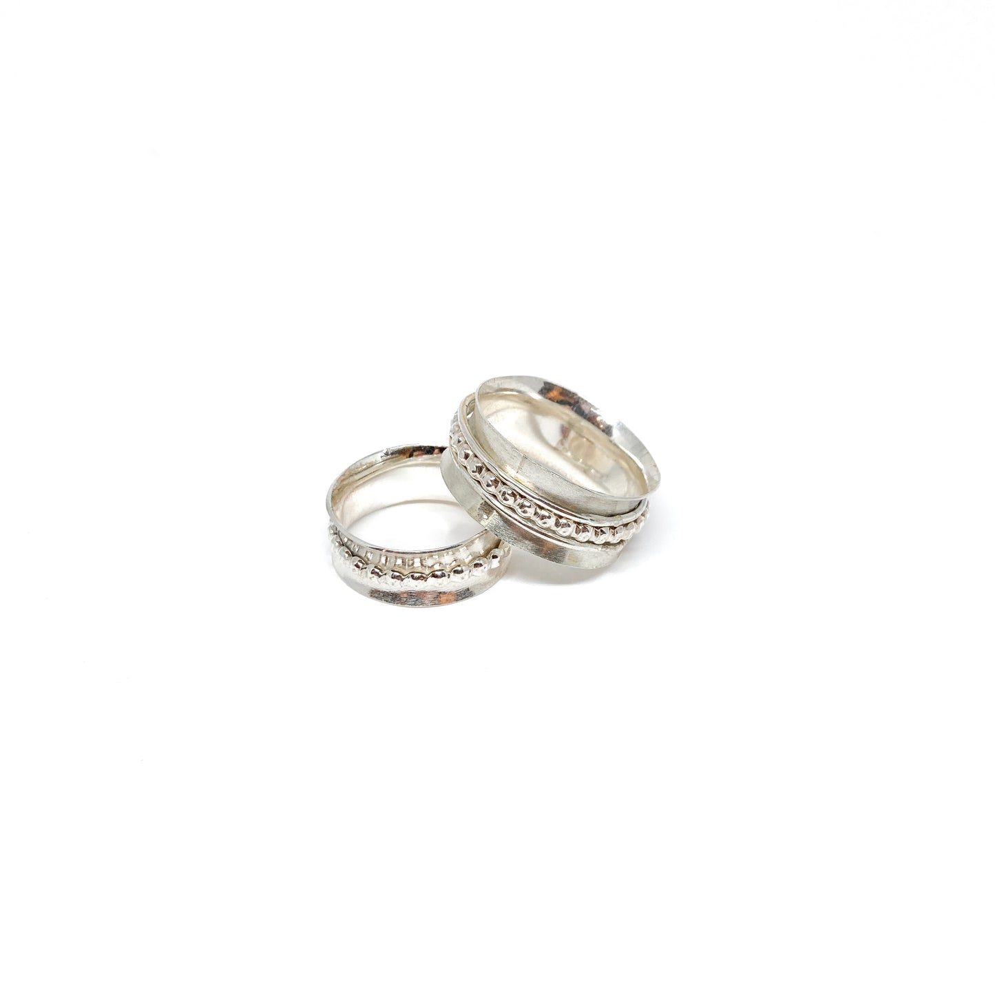 Two silver spinner rings, one stacked, with textured spinning bands featuring dot and line patterns.