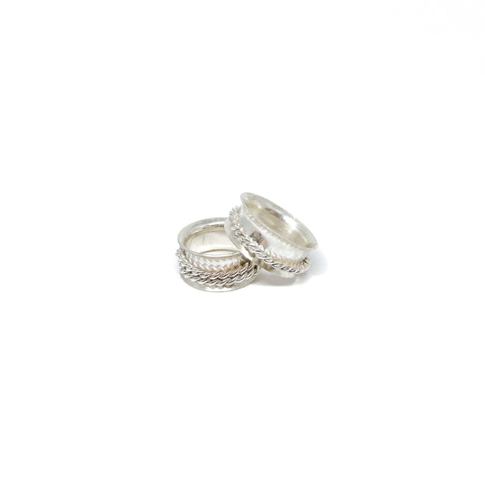 Two textured silver spinner rings, one stacked on the other, with a braided band detail.