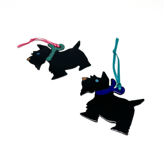 Black Scottie dog ornament with a gold hook and ribbon, hanging from a Christmas tree.