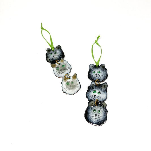 Two hanging ornaments with three stacked cat faces each, attached by small gold rings and green ribbons.