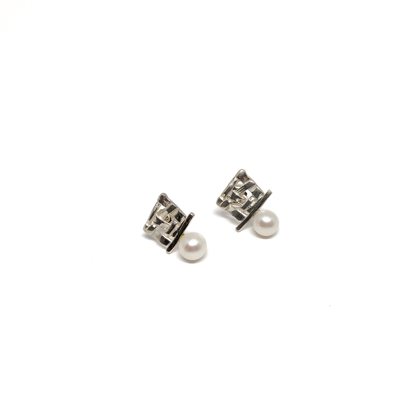 A pair of silver stud earrings with a square woven design and a single pearl accent on each. The earrings have a post back closure.