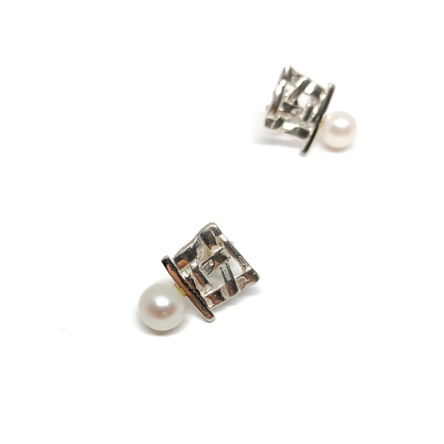 A pair of silver stud earrings with a square woven design and a single pearl accent on each. The earrings have a post back closure.