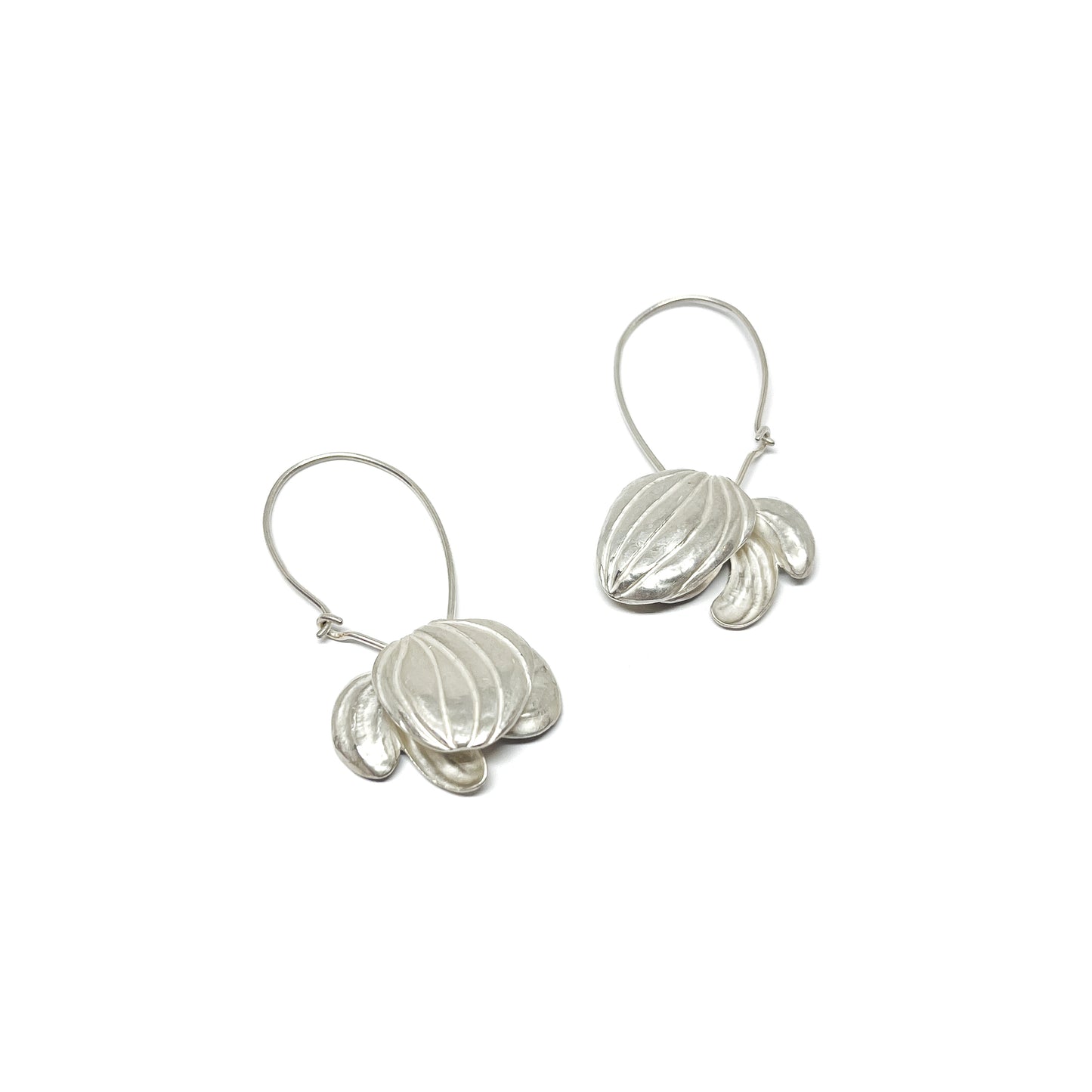 A pair of silver hoop earrings with textured, abstract floral or shell-like pendants dangling from the delicate loops.