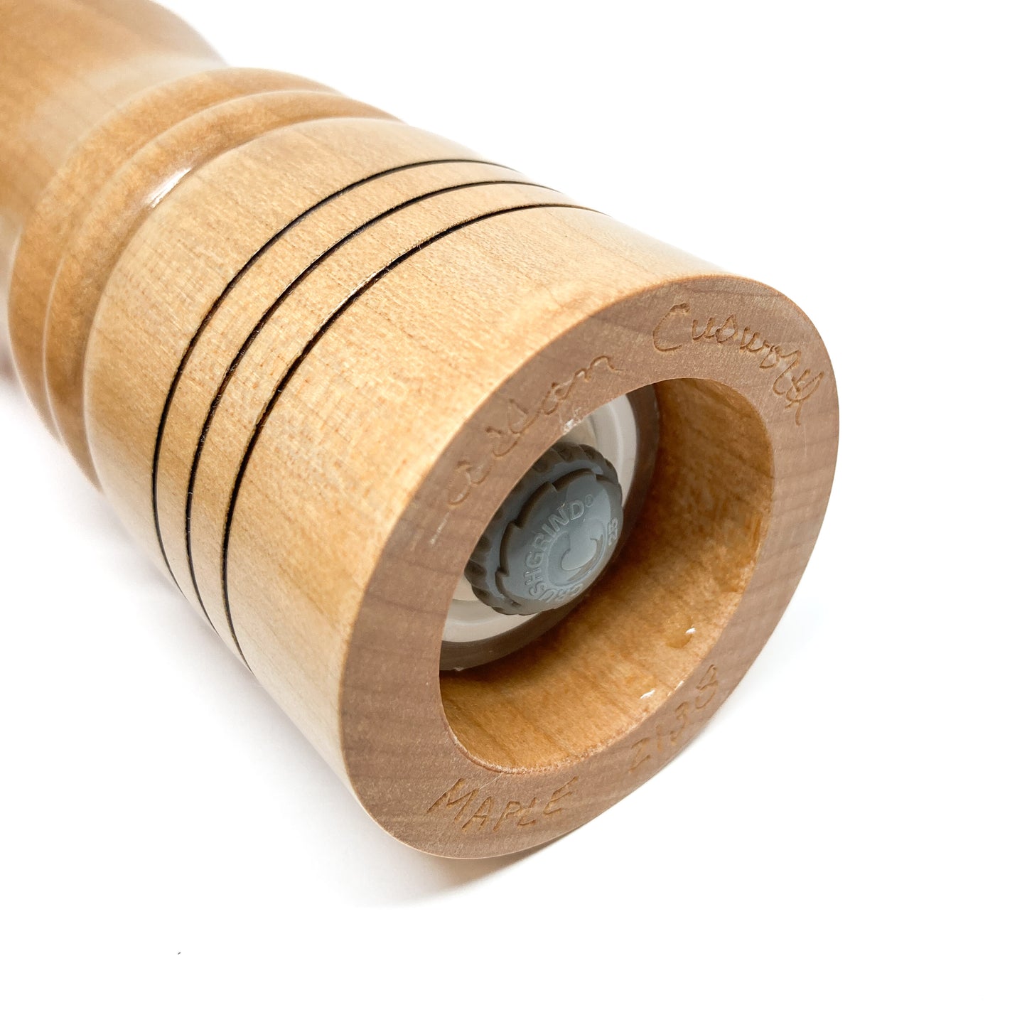 Wooden pepper mill end, close-up with ring details and grinder visible.