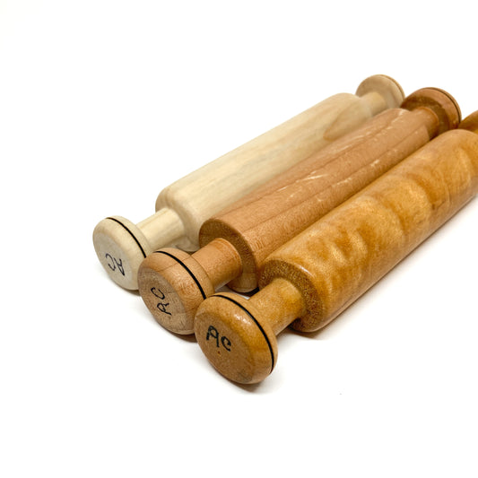 Three rolling pins with "AC" initials, different wood tones, angled shot.