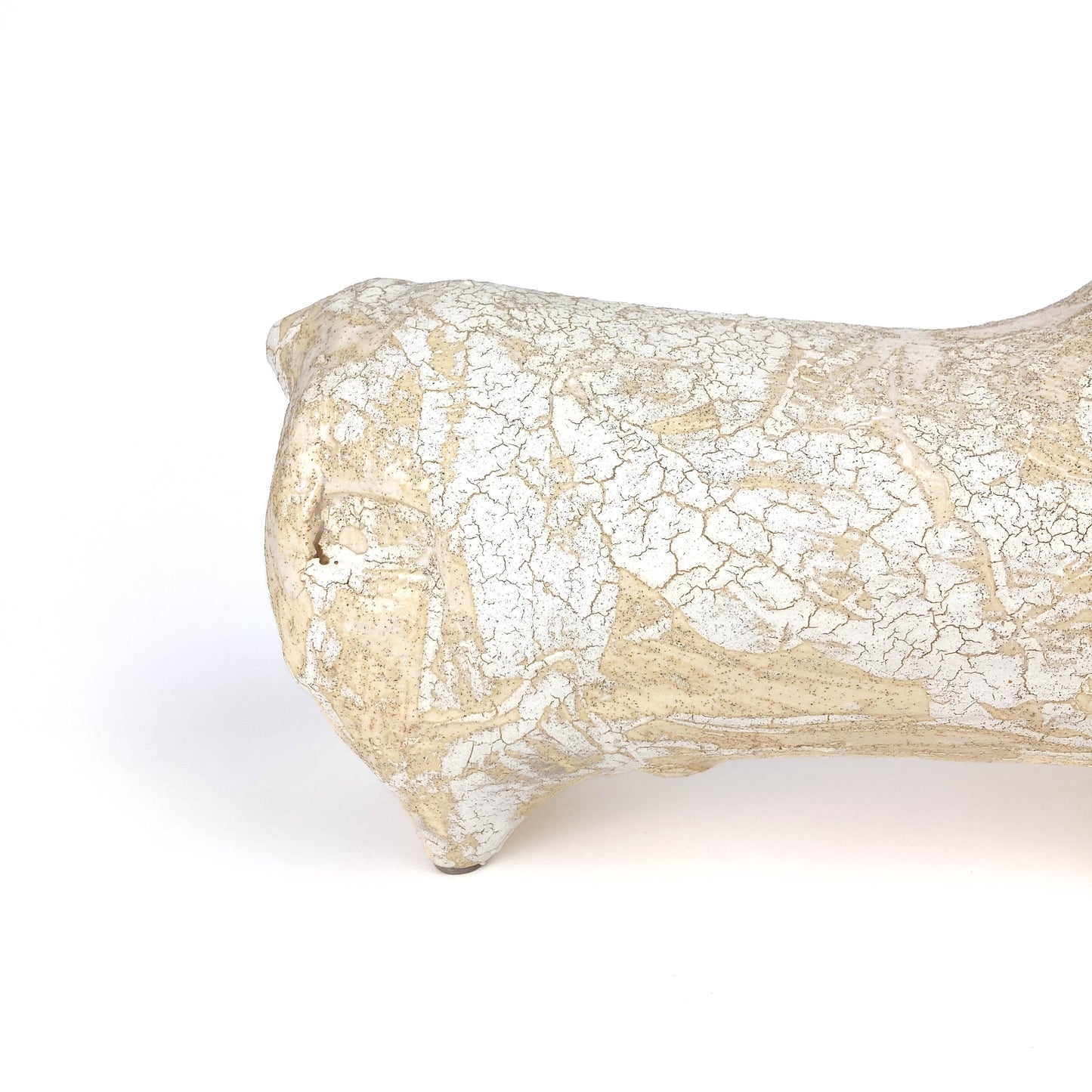 Partial view of a textured, light-toned ceramic bull figurine's rear with a raised tail and crackled glaze.