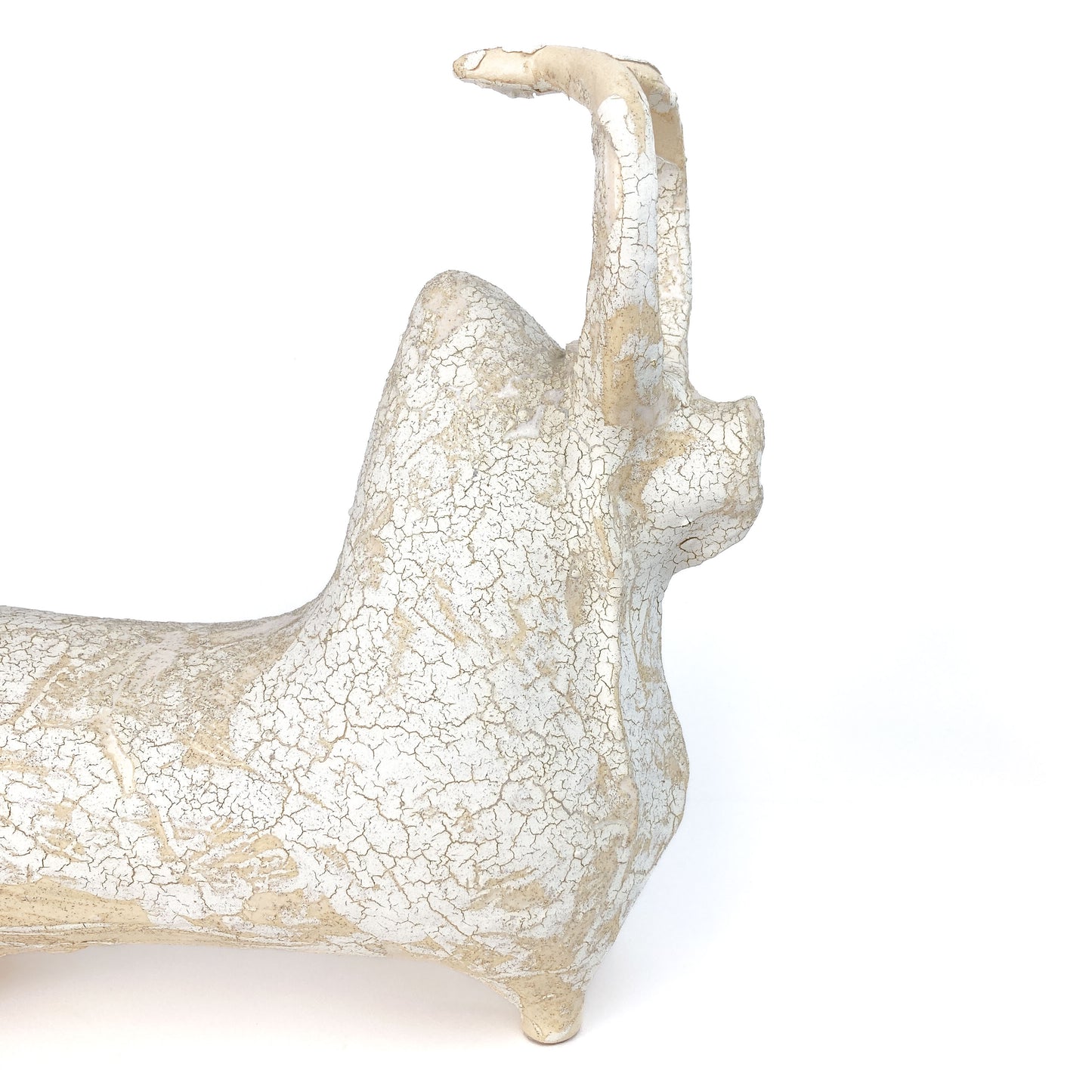 A textured, light-toned ceramic bull figurine with its head and tail raised, featuring a distinct crackled glaze.