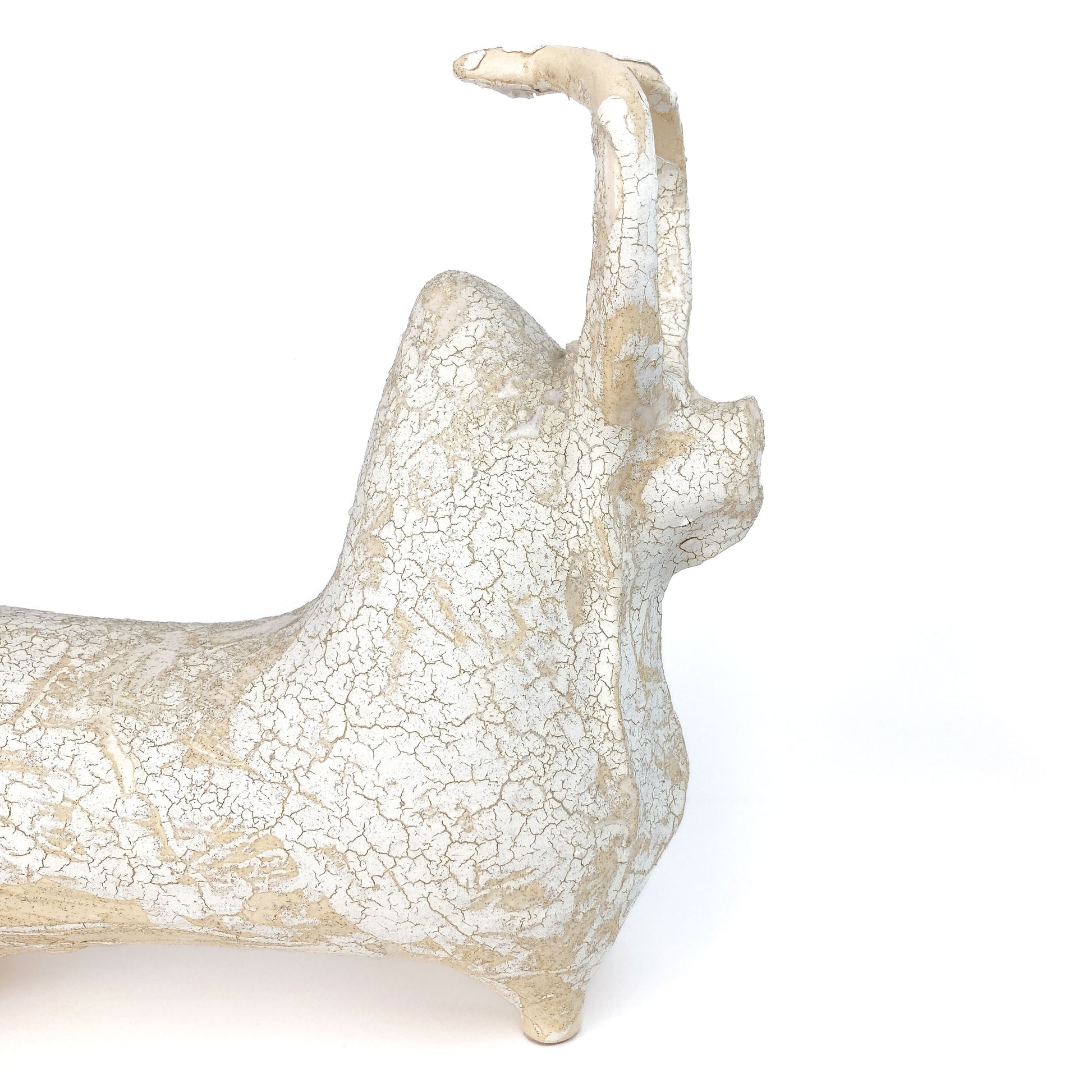 A textured, light-toned ceramic bull figurine with its head and tail raised, featuring a distinct crackled glaze.