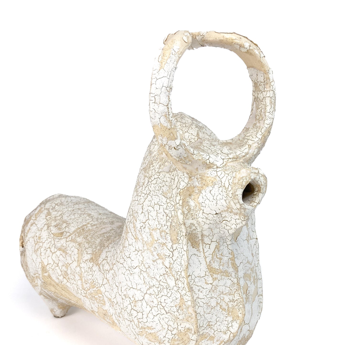 Close-up of a textured ceramic bull figurine's head with a raised horn, snout, and crackled glaze.