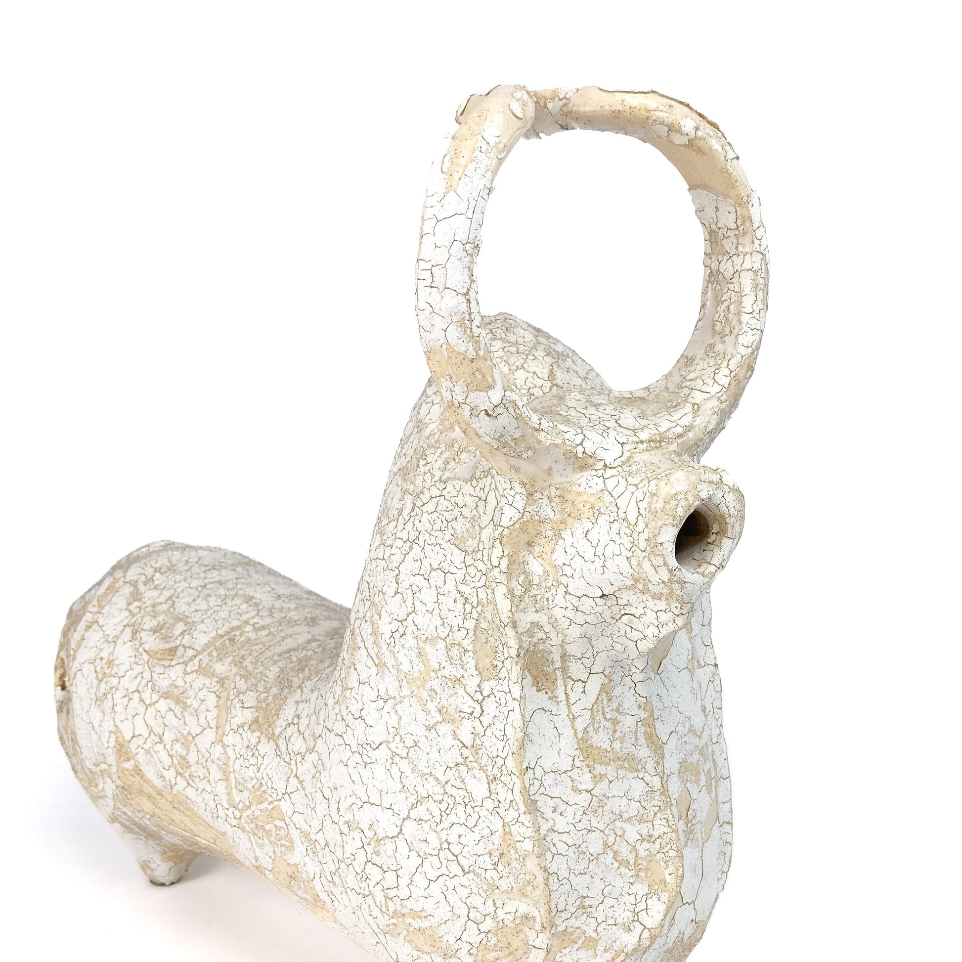 Close-up of a textured ceramic bull figurine's head with a raised horn, snout, and crackled glaze.