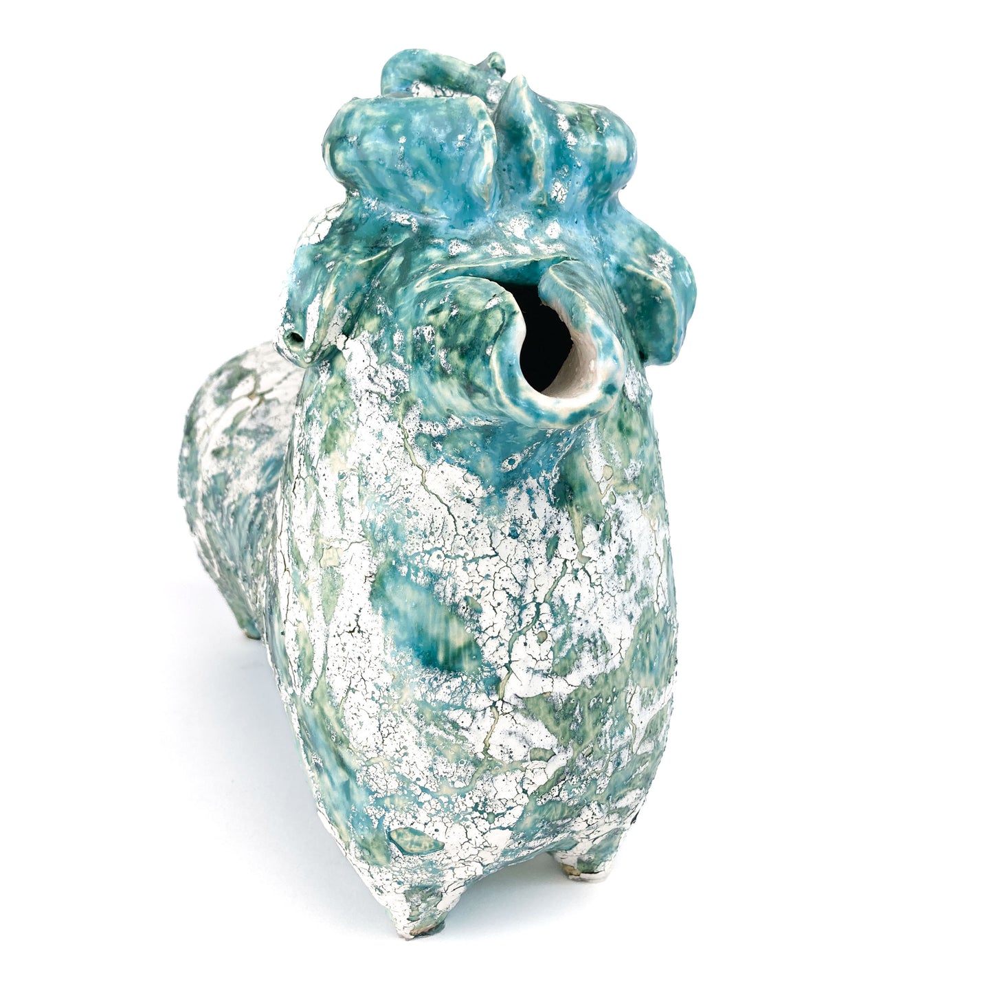 Textured ceramic bull figurine with a teal and white mottled glaze, facing forward with curled horns and a hollow snout.