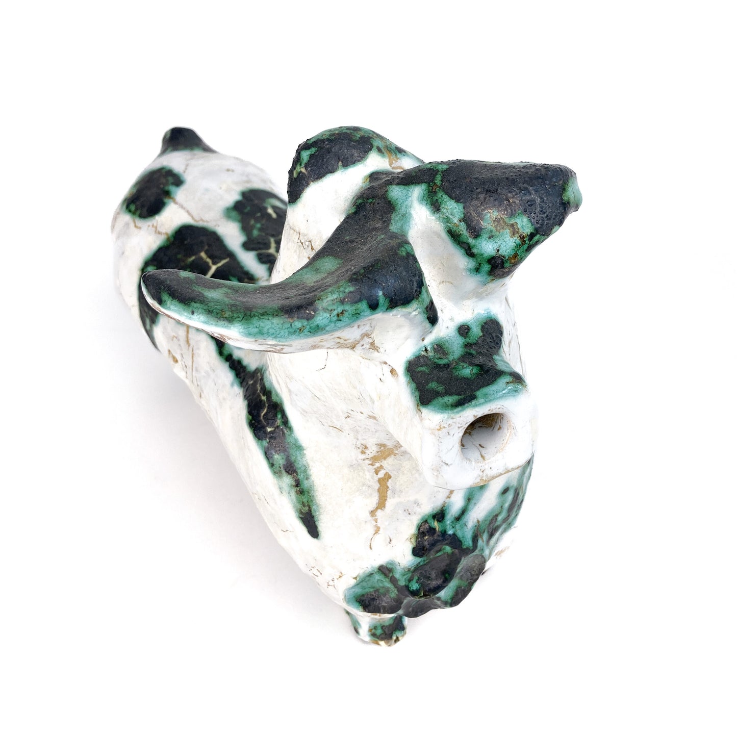 Top-down view of a textured ceramic bull figurine with white, teal, and black mottled markings and a hollow snout.