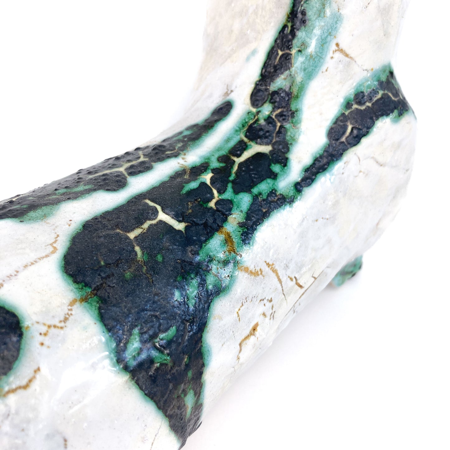 Close-up of the textured body of a ceramic bull figurine with white and mottled teal and black glaze.
