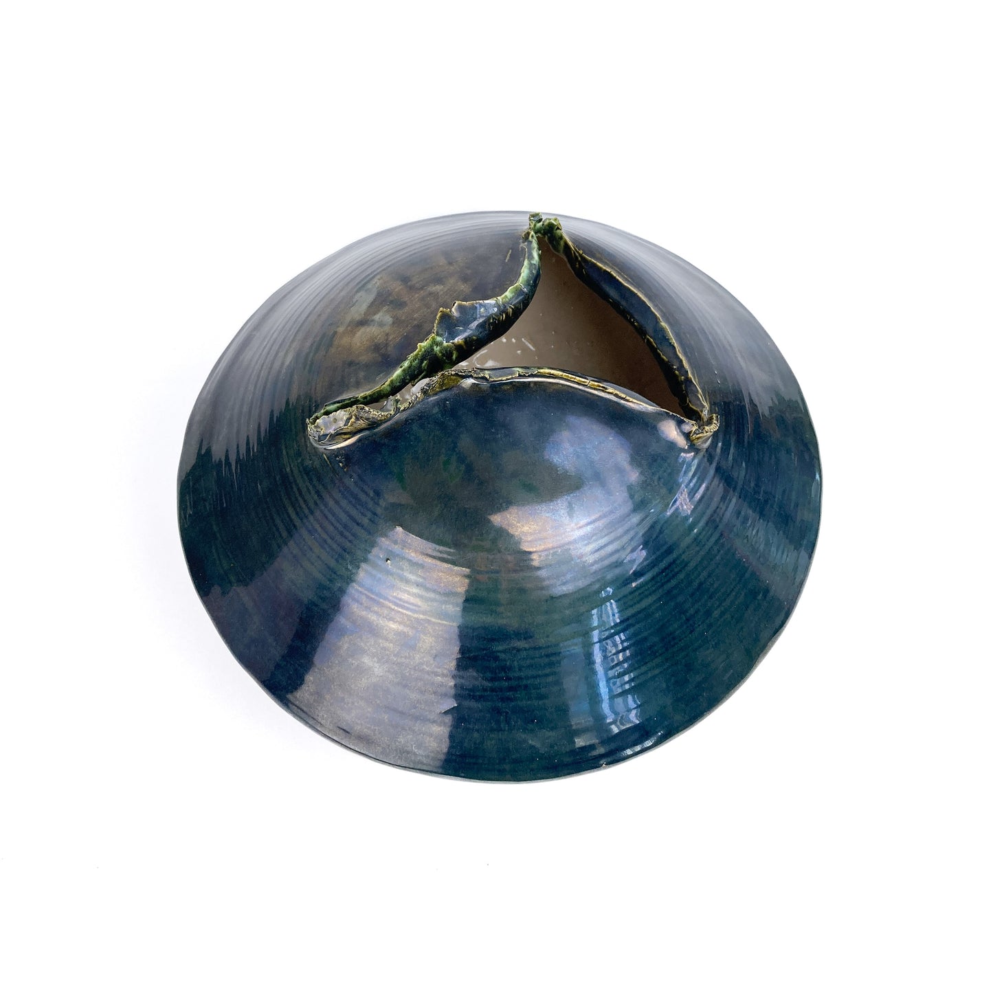 Top-down view of a dark, round ceramic UFO sculpture with a textured, jagged opening revealing a lighter interior.