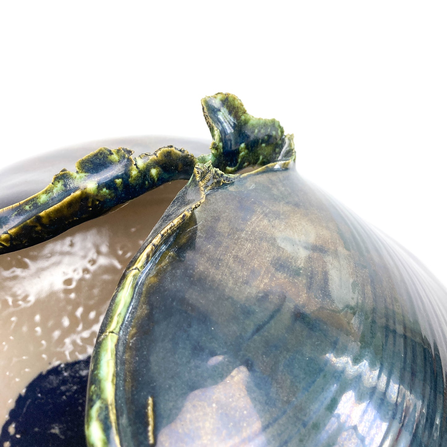Extreme close-up of the textured, jagged rim of a dark ceramic UFO sculpture, revealing a lighter interior.