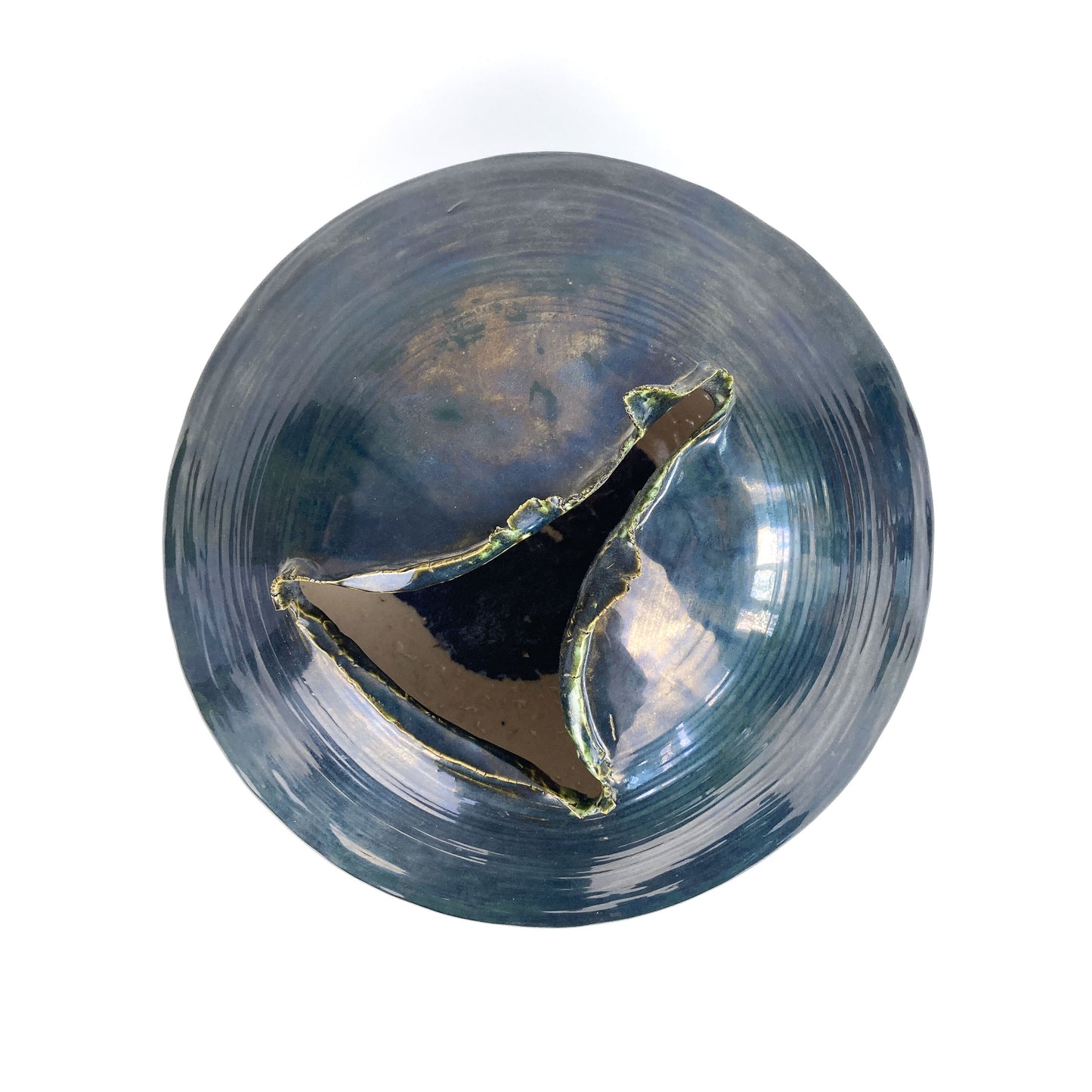 Top-down view of a round, dark ceramic UFO sculpture with a uniquely shaped opening revealing a dark interior.