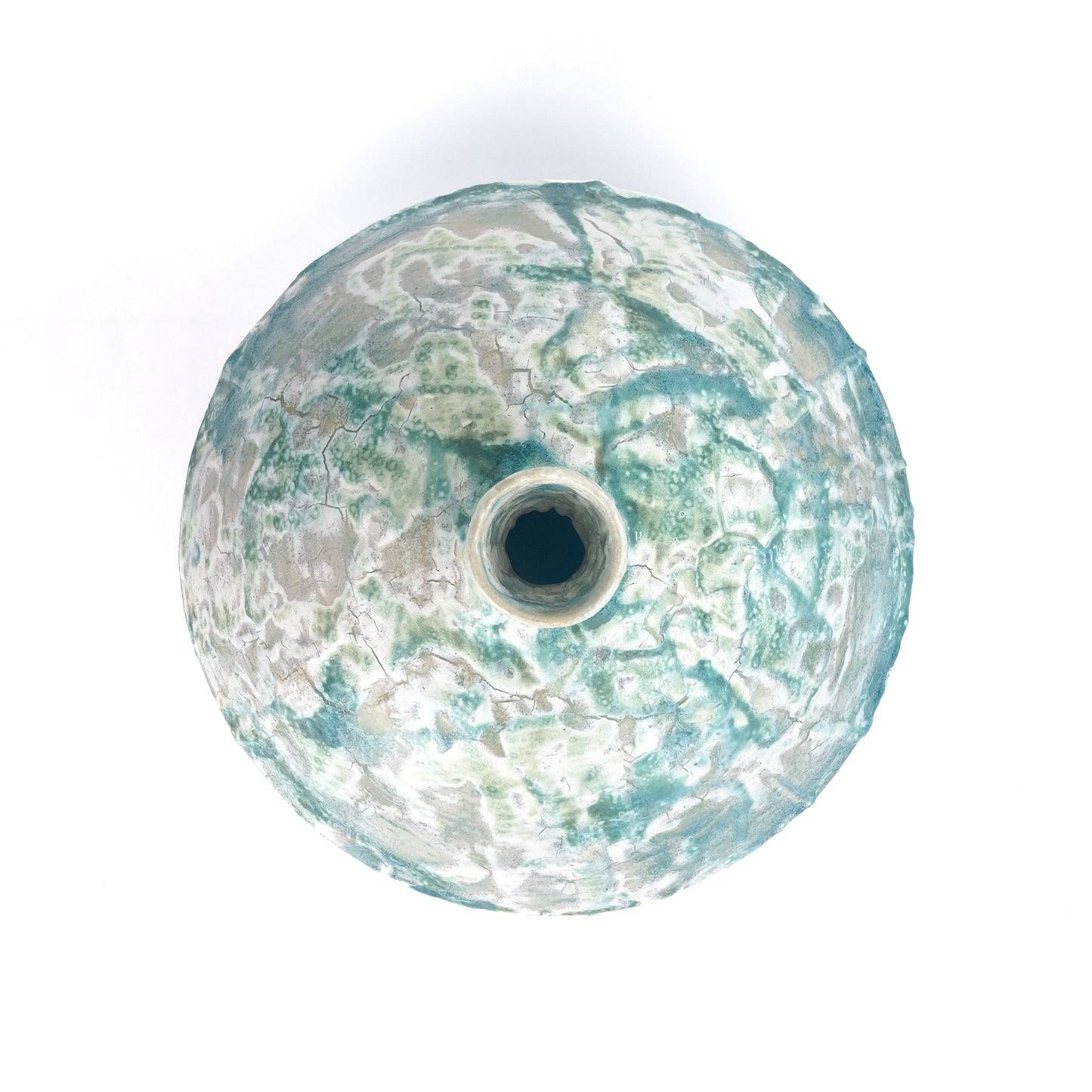 Top-down view of a textured ceramic UFO vessel with a central opening and a mottled teal and light beige crackled glaze.