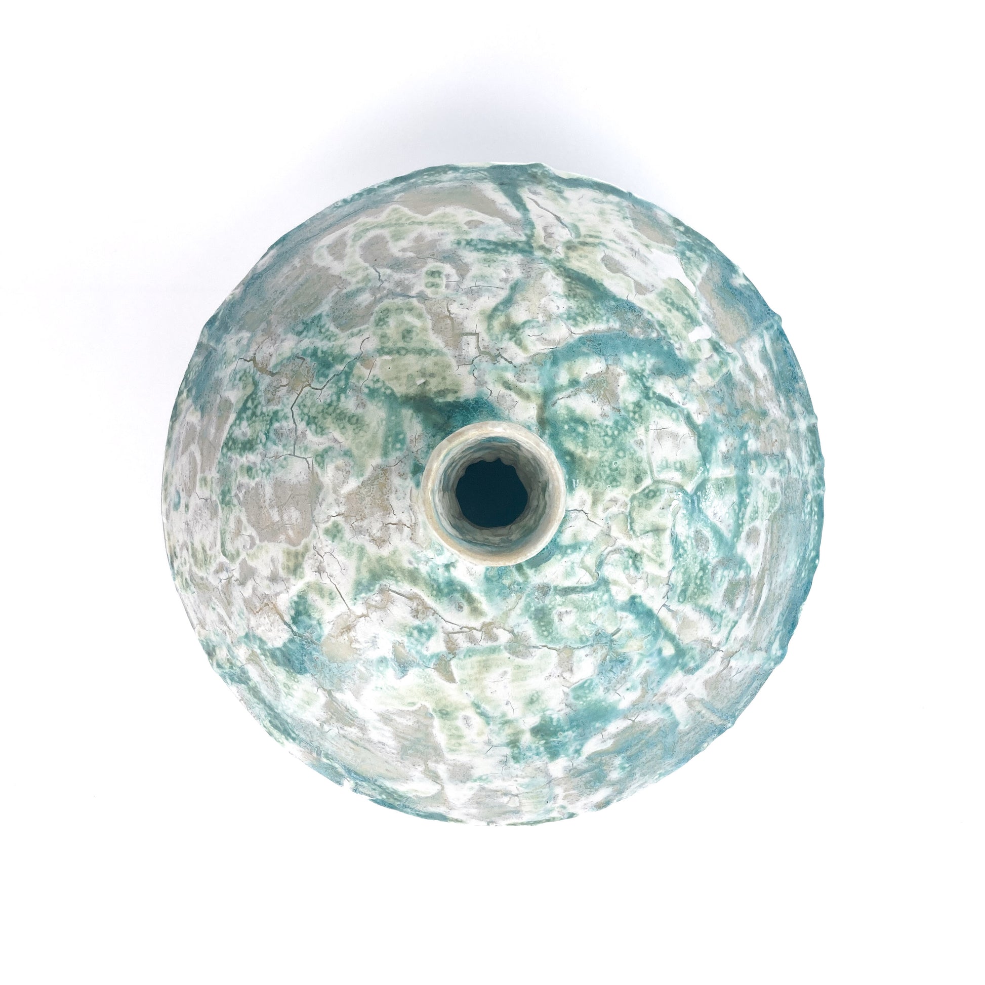 Top-down view of a textured ceramic UFO vessel with a central opening and a mottled teal and light beige crackled glaze.