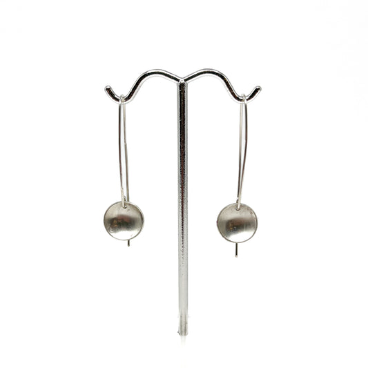 Silver disk drop earrings displayed on a stand.