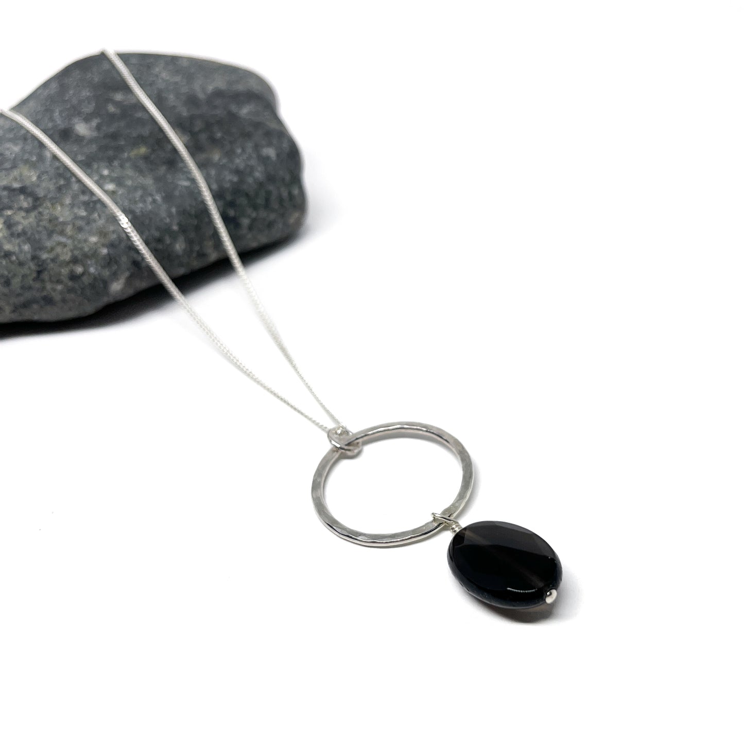 Silver loop necklace featuring a smooth, solid black oval gem pendant.