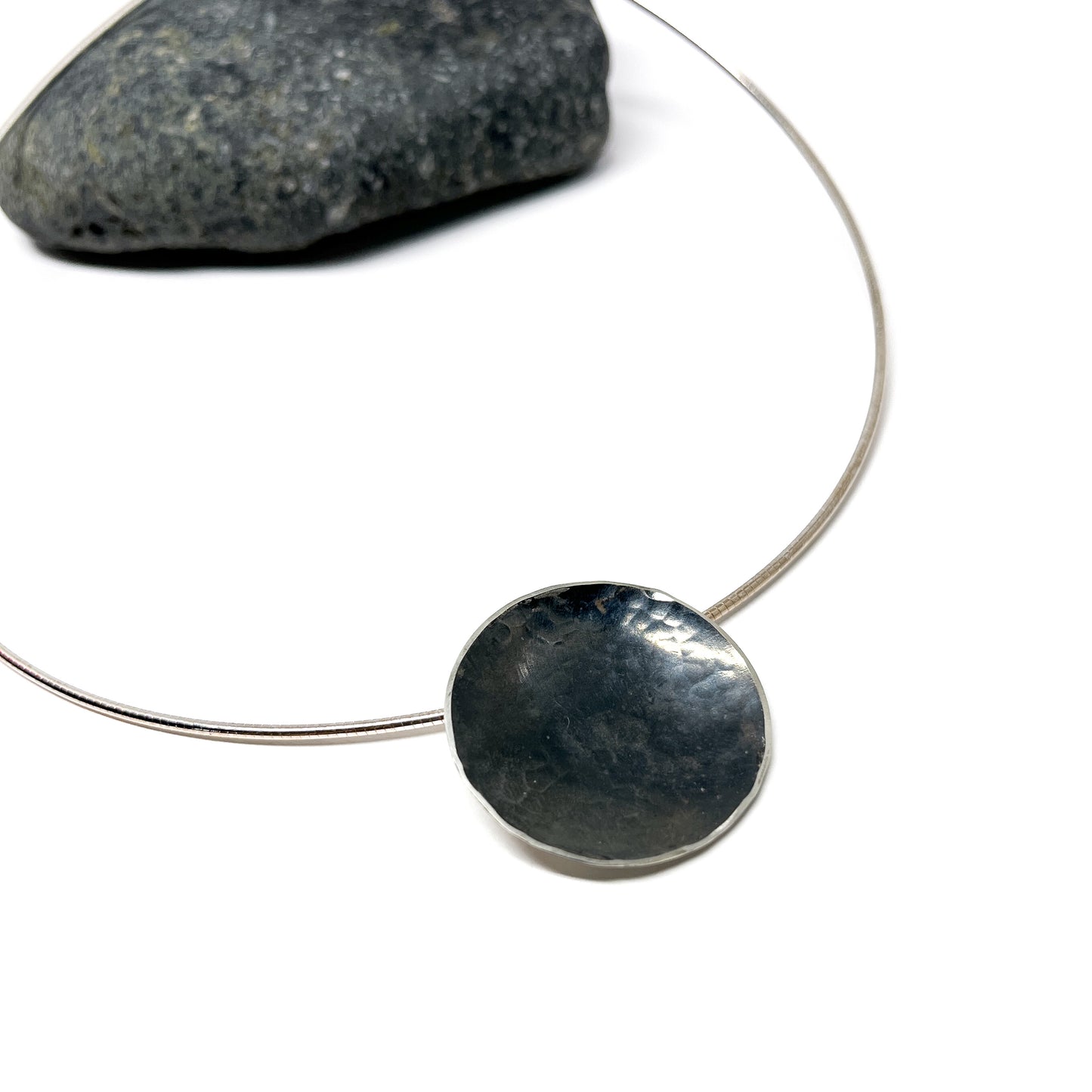 Close-up of the hammered texture on the dark, circular Moonspace Pendant.