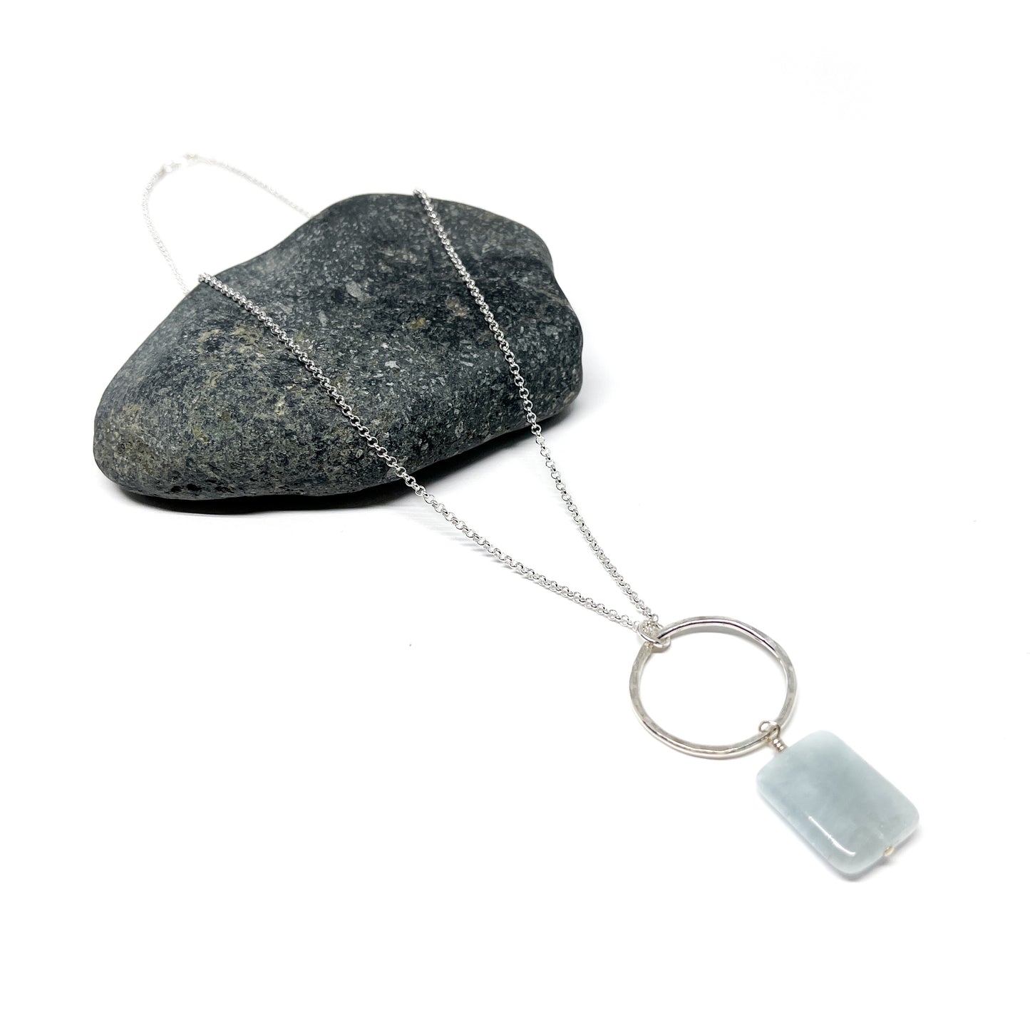 Silver loop pendant necklace with a rectangular, pale blue gem.