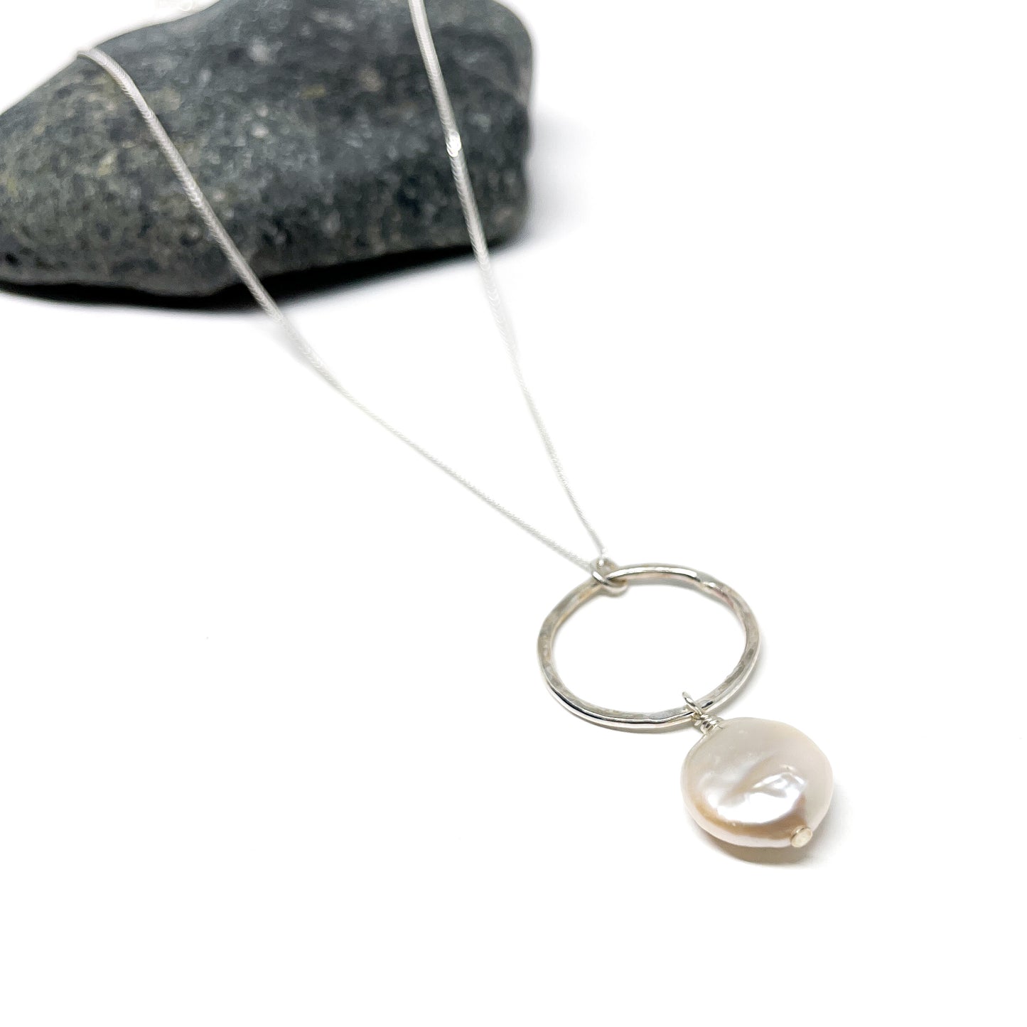 Delicate silver chain necklace featuring a hammered loop and a luminous baroque pearl.