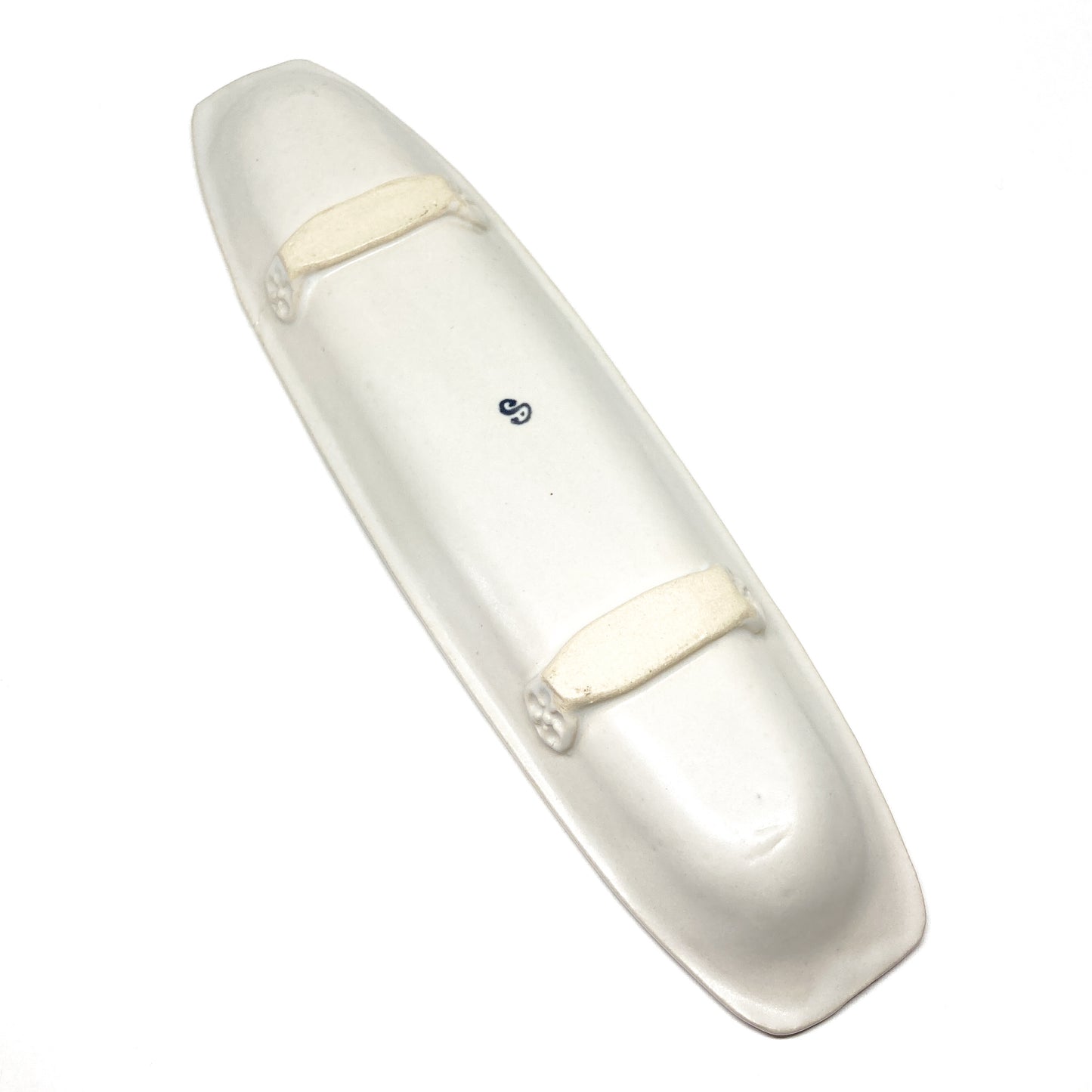 A long, narrow, white olive dish with raised details and a blue "S" in the center.