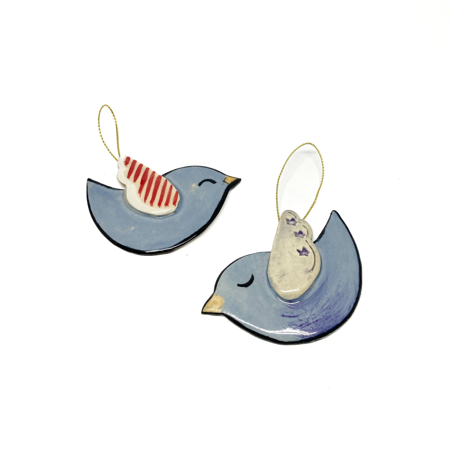 Two light blue bird ornaments with different wing patterns and gold strings.