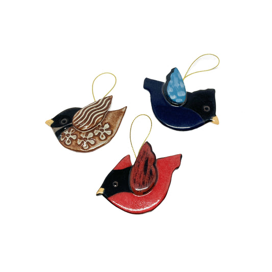 Three bird ornaments with different wing patterns and colors, viewed from above.